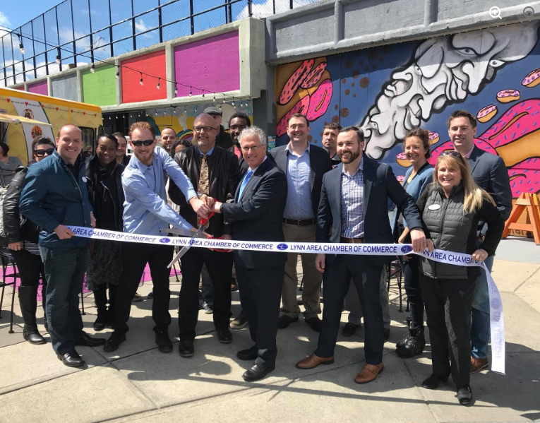 Ribbon-cutting photograph at Ironbound Marketplace, with a group of people standing behind a chamber of commerce ribbon.